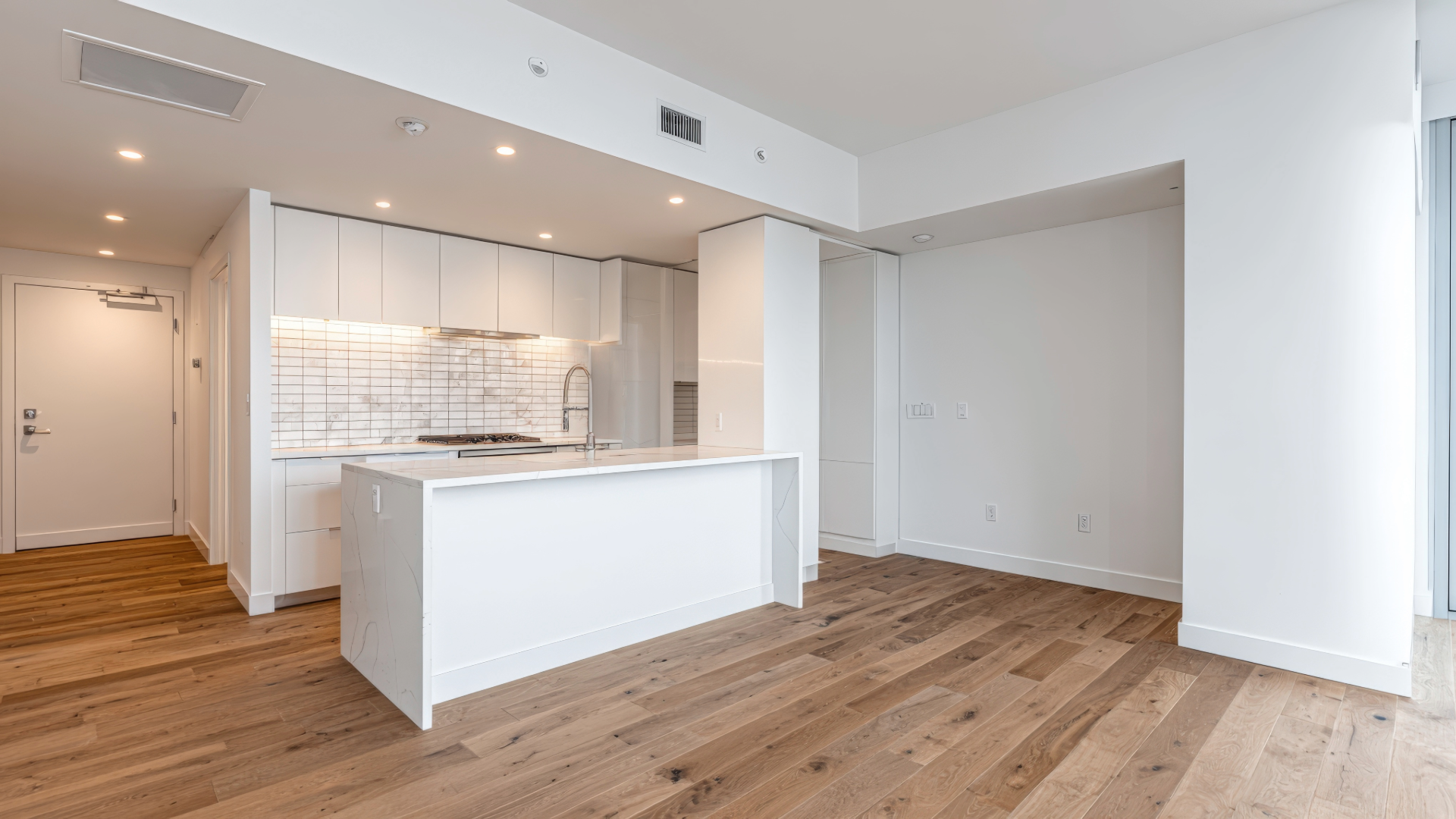 Florida condo remodel featuring a modern white kitchen with light wood floors